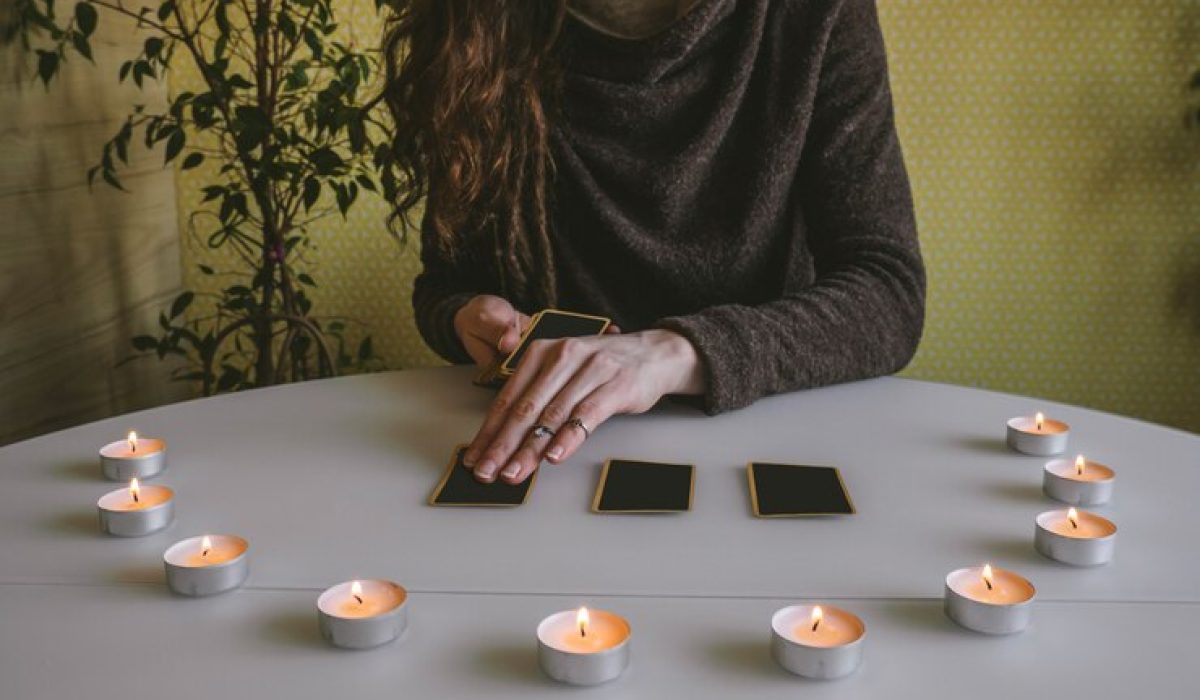 young-woman-lays-out-black-cards-table-with-candle-lights_88775-1380